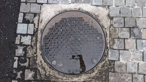 Yerde bir delik olan metal plaka.