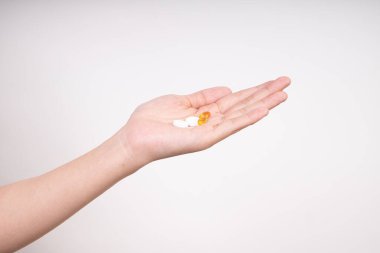 Kadın elleri birden fazla hap, D3 ve Zinc vitamini alıyor. Beyaz arka planda izole edilmiş günlük vitaminler.