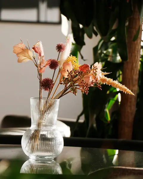 stock image beautiful dry flowers with vase in a glass table