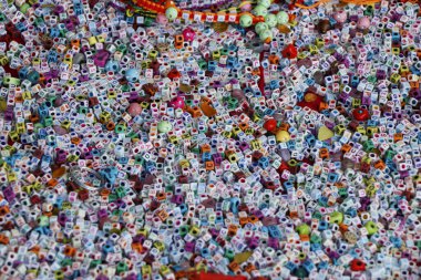 Bilezik dokumak için renkli boncuklar. Bir sürü akrilik küp şeklinde alfabe harfi boncukları. Dikiş işi kavramı.