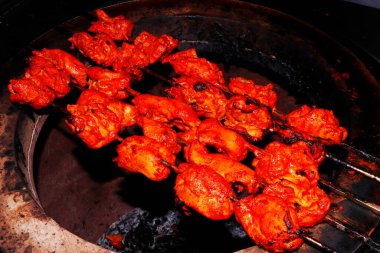 Hint tandoor olarak bilinen kil bir fırında pişirilen baharatlı marine edilmiş tavuk kübü (tavuk tikka) şişleri