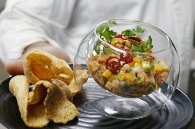 Deniz ürünleri ceviche 'si ya da elinde kraker olan cam bir kasede tartar.