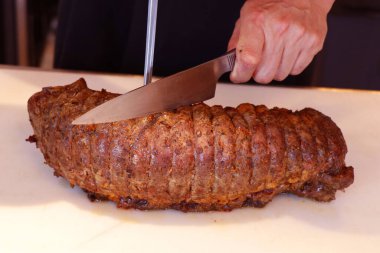 Salamura edilmiş otlar ve beyaz bir tahta üzerinde fırında biftek pirzolası, festival sezonu için oymaya hazır.