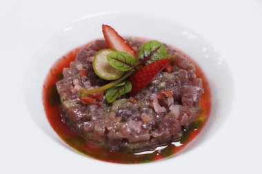 Akdeniz yemeği spesiyali, beyaz tabakta çilekli ton balığı.