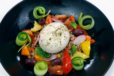 Akdeniz usulü mozarella mozzarella kinoa salatası, siyah tabakta.