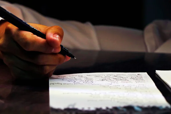 a person writing on a paper with ball pen in close up