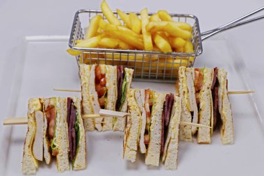 Domuz pastırmalı sandviç, tavuk, domates ve marul. Patates kızartması ile servis edilir.