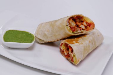 Tortilla ekmeğine sarılı tavuk tikka, nane sosuyla servis edilir.