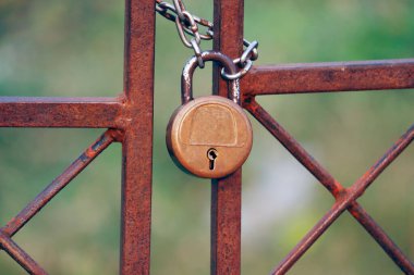 Metal giriş kapısına asma kilit ve güçlü çelik zincir dolanmış.