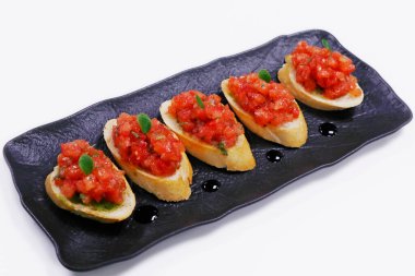Klasik domates bruschetta, zeytinyağı ve fesleğenle terbiye edilmiş taze domates küpleri ve kızarmış ekmek.