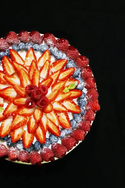 fruit cake decorated with assorted mixed berries with black background