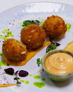 Baharatlı mayonez ve beyaz tabakta kızarmış köfte.
