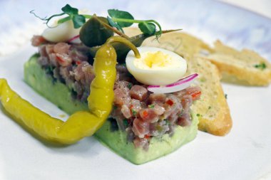 Avokado püresi, bıldırcın yumurtası ve cips ile ton balıklı tartar.