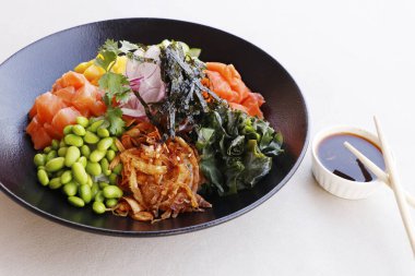 Japon poke kasesi edamame, somon, wakame yosunu, mango, turp, salatalık, soğan ve tatlı soya sosuyla servis edilen pirinç.