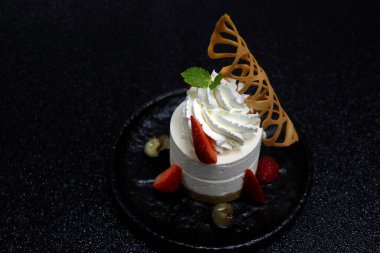 Boru kremalı geleneksel cheesecake ve siyah arkaplanlı taze böğürtlen.