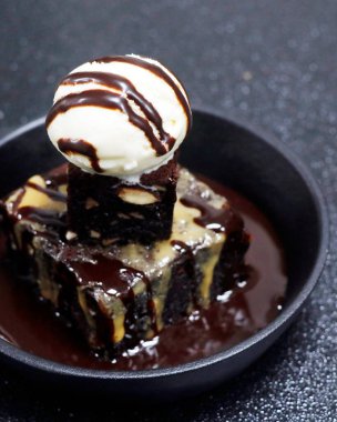 Çikolatalı ve cevizli kek ve siyah arka planda vanilyalı dondurma.