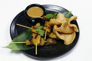 Otantik Asya sokak yemekleri fıstık soslu tavuk satay ve bambu yapraklı karides krakerleri.