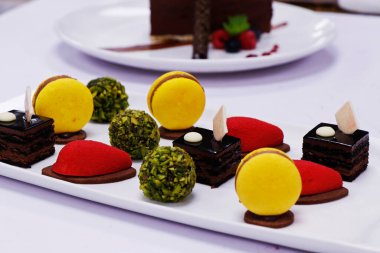 assorted french pastries in a platter as petit four with macaroons, chocolate cake, pistachio balls etc. clipart