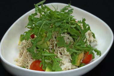 Dilimlenmiş tavukla yapılmış tavuk salatası ve sosla karışık yeşillikler.