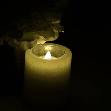 Siyah arka planlı mum ışığı, canlı bir kibir.