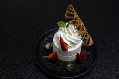 Boru kremalı geleneksel cheesecake ve siyah arkaplanlı taze böğürtlen.