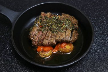 İspanyol chimichurri bifteği patates ve baharatlı brava soslu siyah arka planda.