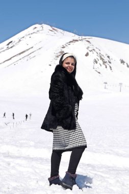 Güzel genç bayan kışın kar dağında eğleniyor.