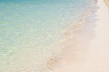 Kumsalda ve sahilde şeffaf su dalgaları var.