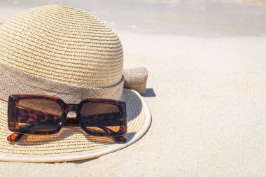 Hasır şapkalı ve deniz zeminli güneş gözlükleri.