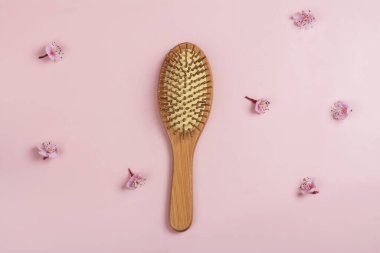 Pembe ve sakura çiçekli bambu saç fırçası. Uluslararası Saç Günü. Kötü saç geçmişi. Uzayı kopyala Üst görünüm