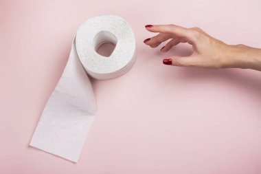 Tuvalet kağıdı rulosu ve kadınların eli pembe arka planda. Uluslararası tuvalet kağıdı günü. Üst görünüm