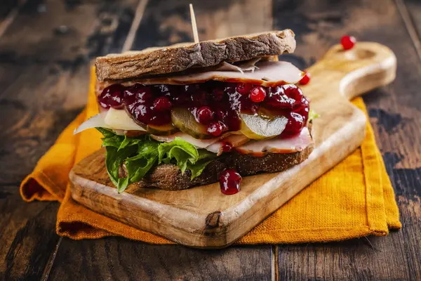 Homemade leftover thanksgiving day sandwich with turkey, cranberry sauce and vegetables. Dark rustic style