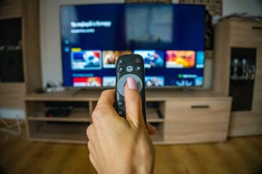 Çekim akışı. Akıllı TV seyreden ve uzaktan kumandalı uzaktan kumanda kullanan yaşlı bir kadın. Uzaktan kumandalı televizyon uzaktan kumandalı Ortanca Kadın Televizyon dizisi evde vakit geçiriyor. Yüksek kalite fotoğraf