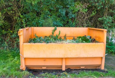 Şehir caddesinde çöp toplamak için tekerlekli turuncu büyük bir çöp kutusu. Temiz bir çevreye önem vermek. Yeşil çimenler. Çek malı. Yüksek kalite fotoğraf