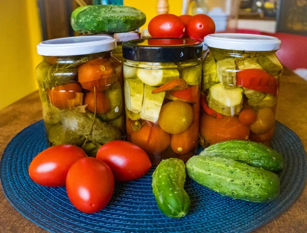 Glass jars with pickled cucumbers pickles, pickled tomatoes and cabbage. Jars of various pickled vegetables. Canned food in a rustic composition. High quality photo
