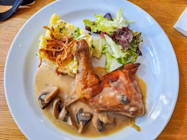 Tasty cooked chicken legs with potatoes, cabbage, mushrooms on a white plate. Delicious potatoes with onion and dill on dinner, lunch. Amazing chicken legs cooked in spice. Ukrainian healthy meal .