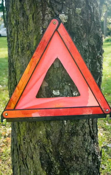 Red triangle, red emergency stop sign, red emergency symbol. On a tree. Beware of the tree. High quality photo