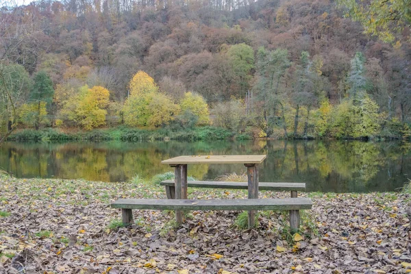 Picnic wooden benches and table by the river Berunka in autumn season, place to relax with forest and mountains. High quality photo