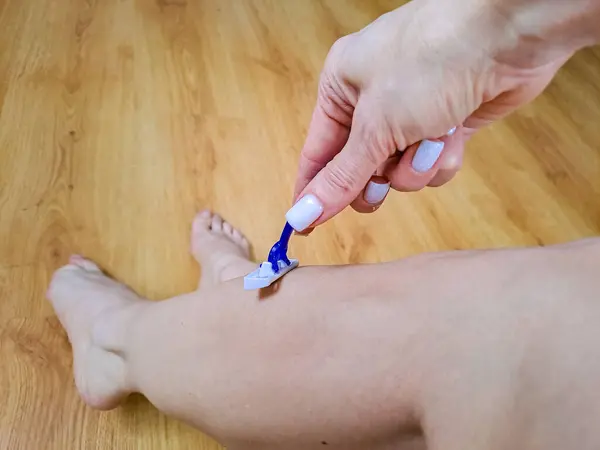 Skin Care and Health. Hair Removal. Fit Woman Shaving Her Legs With Razor. High quality photo