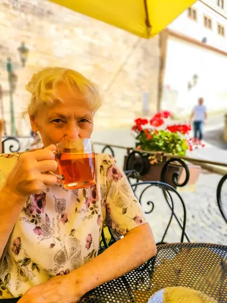 Old lady wearing jewelry having tea at a restaurant in Prague. Czech High quality photo