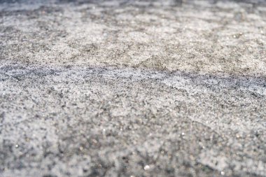 Çakıl taşlarının yüzeyi buzla, buzla, buzla kaplı. Kışın karlar içinde kaya levhaları. Geçmişi. Yağmurlu günler beton yol yüzeyinde su dalgalarına neden olur. yakın plan