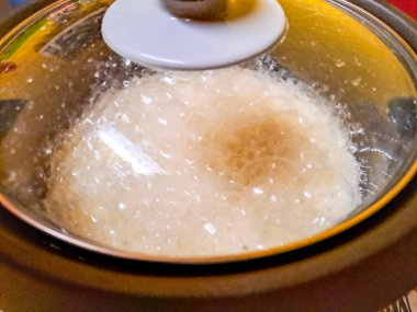 Pilav makinesinde taze pişmiş beyaz pirinç. Mutfaktaki elektrikli pilav pişiricisinin buharı. Odaklan. Sıcak yemek konsepti.