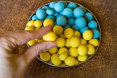 Mavi ve sarı çikolatalı dragee. Ukrayna bayrağı olarak, desteğin şerefine. Beyaz ahşap arka planda çikolatalı sürahi. Kapat. Yüksek kalite fotoğraf