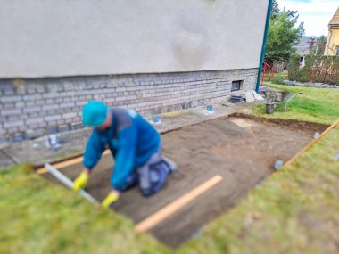 Evin avlusundaki verandaya gri beton döşeme döşemesi. Profesyonel işçiler yeni fayanslar veya levhalar döşüyorlar Seviyeli kum temeli üzerine garaj yolu, kaldırım veya veranda için.