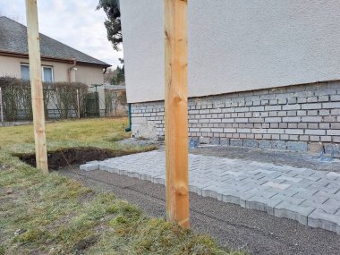 Evin avlusundaki verandaya gri beton döşeme döşemesi. Profesyonel işçiler yeni fayanslar veya levhalar döşüyorlar Seviyeli kum temeli üzerine garaj yolu, kaldırım veya veranda için.