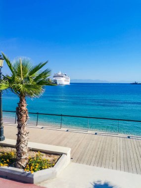 Rodos limanına büyük mavi bir yolcu gemisi yanaştı. Yakınlarda çeşitli gemiler demirli, palmiye ağaçları yetişiyor ve ortaçağ binaları görülebilir durumda. Rodos. Yüksek kalite fotoğraf