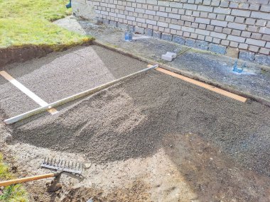 Evin avlusundaki verandaya gri beton döşeme döşemesi. Profesyonel işçiler yeni fayanslar veya levhalar döşüyorlar Seviyeli kum temeli üzerine garaj yolu, kaldırım veya veranda için.