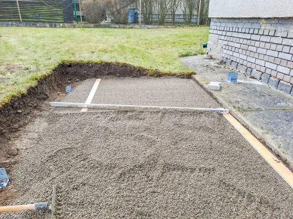 Evin avlusundaki verandaya gri beton döşeme döşemesi. Profesyonel işçiler yeni fayanslar veya levhalar döşüyorlar Seviyeli kum temeli üzerine garaj yolu, kaldırım veya veranda için.