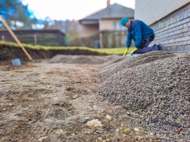 Evin avlusundaki verandaya gri beton döşeme döşemesi. Profesyonel işçiler yeni fayanslar veya levhalar döşüyorlar Seviyeli kum temeli üzerine garaj yolu, kaldırım veya veranda için.