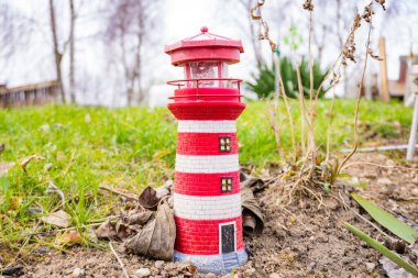 lighthouse. red and white toy lighthouse on natural background. In Early Spring time, river holidays, travel concept. High quality photo clipart
